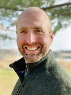 Dr. Adam Moir, seen from the shoulders up, wearing a green sweater and smiling
